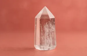 Cristallo di Rocca naturale su sfondo rosso sfumato, simbolo di energia, purezza e skincare energetica.