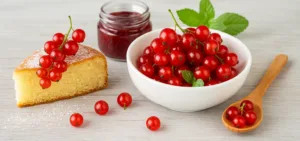 Ribes in cucina: ciotola di ribes rosso, fetta di torta e confettura su tavolo chiaro