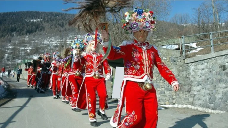 Maschere rosse del Carnevale della Coumba Freida in sfilata lungo il borgo
