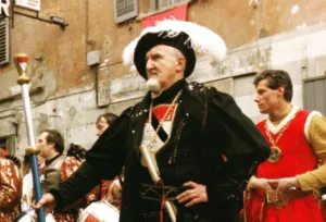 Figurante in costume medievale al Carnevale di Verrès con abiti storici e tamburini sullo sfondo